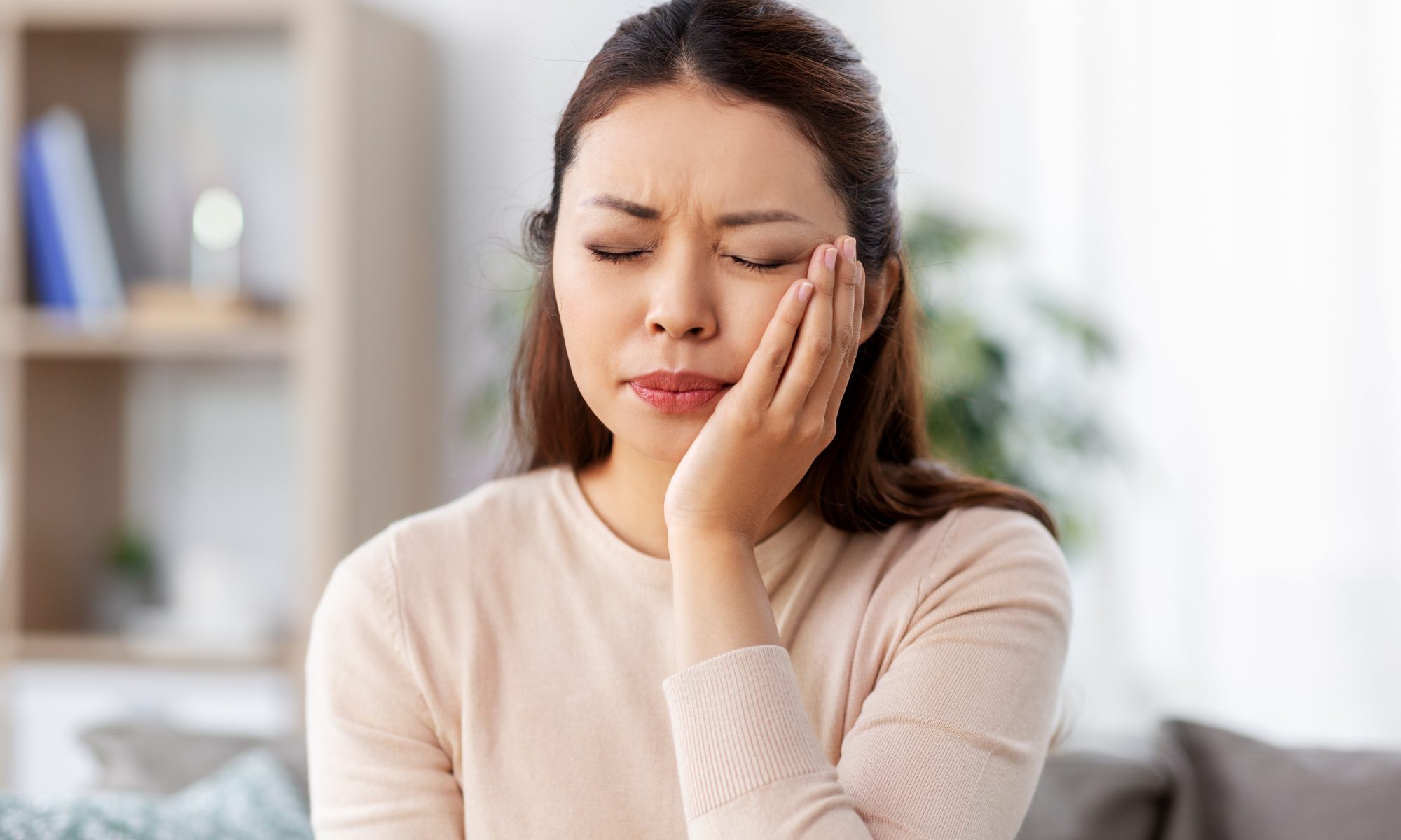 unhappy woman suffering from toothache at home